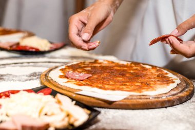 Çocukların elleri lezzetli pizzalar yapıyor.