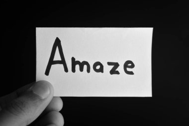 Üzerinde AMAZE yazan bir kart tutuyor.