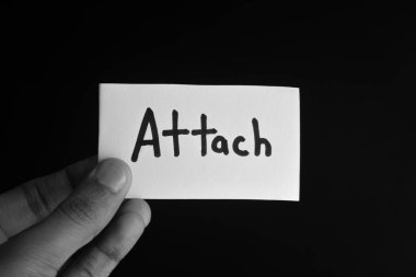 Elinde ATTACH sözcüğünün yazılı olduğu bir kart var.