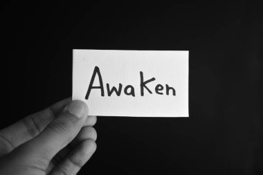 Elinde AWAKEN yazan bir kart tutuyordu.