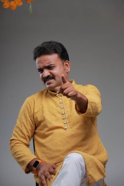 Geleneksel Hint kostümlü, sade arka planda, izole edilmiş, sarı kurta ve beyaz pijama giyen bir adam..