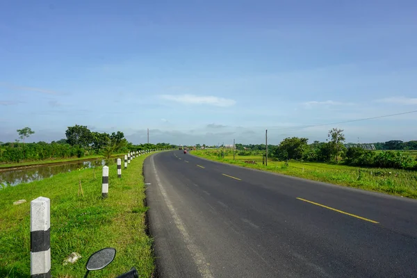 stock image view of a rural asphalt highway with rice fields by the side