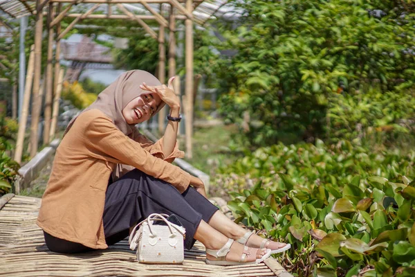美丽的亚洲穆斯林妇女头戴现代头巾坐在花园竹桥上的肖像 — 图库照片