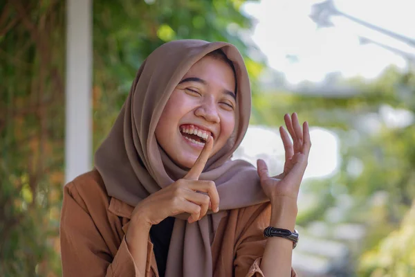 幸せな表情と指を口にしたヒジャーブのアジア系女性です イスラム教徒の女性は大声で笑って — ストック写真