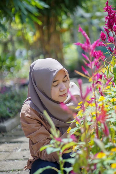 现代头巾上的美丽的亚洲女人的肖像 她在花园里捧着花 喜欢植物的穆斯林妇女 — 图库照片