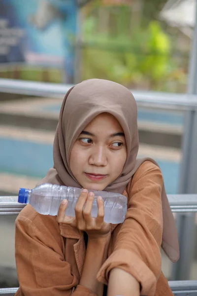 現代のヒジャーブを着た美しいアジア系イスラム教徒の女性が公園で水を持っています — ストック写真