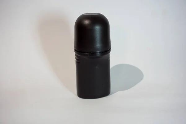 Beyaz arka planı ve siyah gölgesi olan siyah şişe deodorantı.