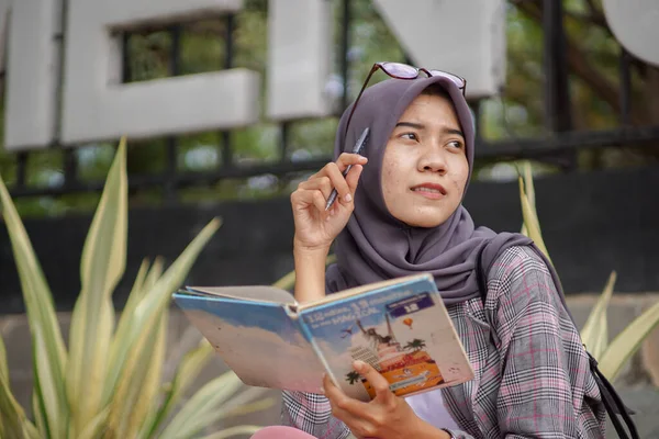 漂亮的亚裔穆斯林妇女 手持书本和钢笔 一个穆斯林妇女举着一本书 想写些什么的姿势 — 图库照片