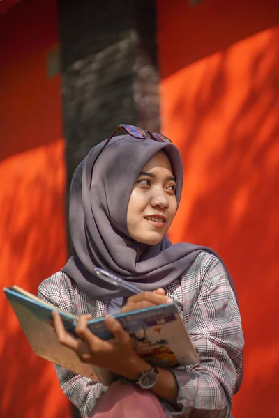 美しいアジアの現代ヒジャーブ ムスリム女性学生が日記とペンを持って公園に座っています — ストック写真