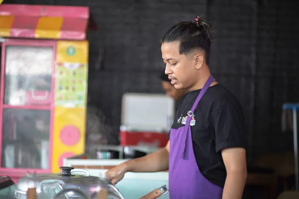 Merkez Java, Endonezya - 03 04: 2023: Genç Asyalı şef, 4 Mart 2023 'te restoran mutfağında müşterilere yemek pişirdi