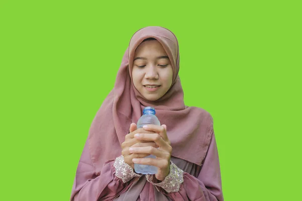 ヒジャーブを履いた美しいアジア系女性が水筒を持っていて緑の背景を持つイフタールの祈りのジェスチャーを示しています イスラム教とラマダーンの概念を持つヒジャーブを着たムスリム女性の写真 — ストック写真