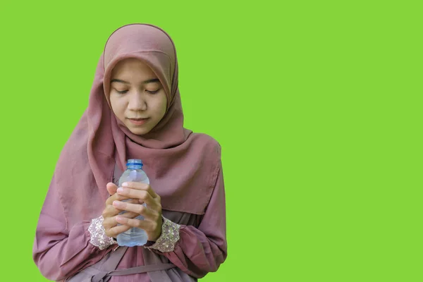 ヒジャーブを履いた美しいアジア系女性が水筒を持っていて緑の背景を持つイフタールの祈りのジェスチャーを示しています イスラム教とラマダーンの概念を持つヒジャーブを着たムスリム女性の写真 — ストック写真