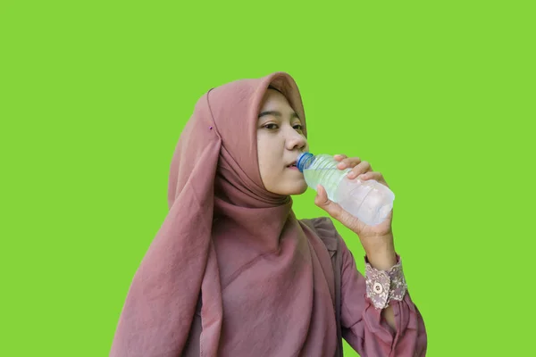 漂亮的亚洲女人 头戴头巾 喝着带绿色背景的瓶装水 穆斯林妇女佩戴带有伊斯兰和斋月观念的头巾的照片 — 图库照片