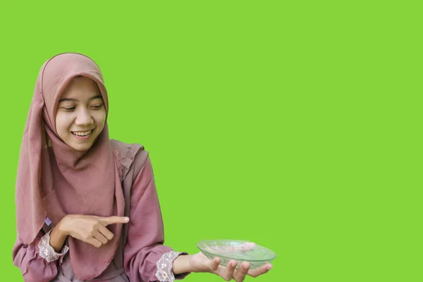 ヒジャーブを身に着けてる美しいアジア系女性緑色の背景で手に持ってる空のプレートを指してる イスラム教とラマダーンの概念を持つヒジャーブを着たムスリム女性の写真 — ストック写真