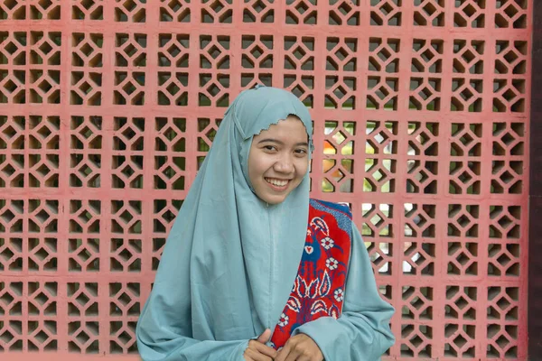 イスラム教の装飾の壁の背景を持つスカーフの祈りの服を着て美しいアジアのイスラム教徒の女性 ムケナという礼服です ラマダーンとイード フィトルのコンセプトを持つムスリム女性の写真 — ストック写真