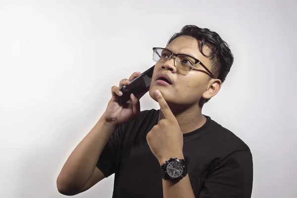 年轻聪明英俊的亚洲男人 身穿黑色T恤 打电话给一个拿着智能手机的人 表达他对白色背景中孤立事物的思考 — 图库照片