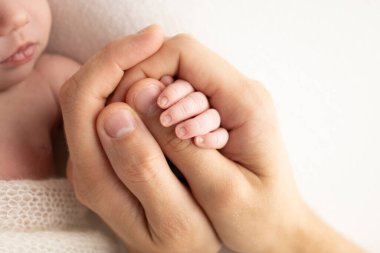 A newborn holds on to moms, dads finger. Hands of parents and baby close up. A child trusts and holds her tight. Tiny fingers of a newborn. The family is holding hands. Concepts of family and love. 