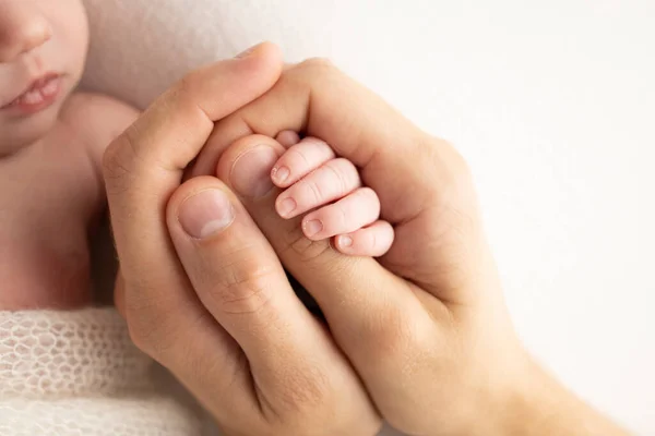 A newborn holds on to moms, dads finger. Hands of parents and baby close up. A child trusts and holds her tight. Tiny fingers of a newborn. The family is holding hands. Concepts of family and love.
