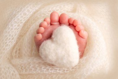 Yünlü battaniyeye sarılmış yeni doğmuş bir bebeğin ayakları. Hamilelik, annelik, annelik hazırlığı ve annelik beklentisi, bir çocuğun doğumu kavramı. Siyah beyaz fotoğraf..