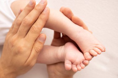 Childrens foot in the hands of mother, father, parents. Feet of a tiny newborn close up. Little baby legs. Mom and her child. Happy family concept. Beautiful concept image of motherhood stock photo.