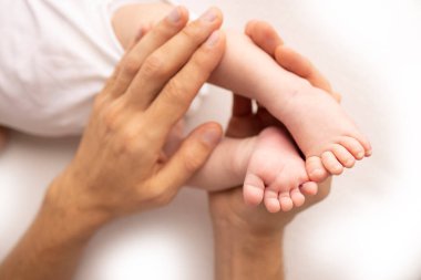 Childrens foot in the hands of mother, father, parents. Feet of a tiny newborn close up. Little baby legs. Mom and her child. Happy family concept. Beautiful concept image of motherhood stock photo.