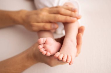 Childrens foot in the hands of mother, father, parents. Feet of a tiny newborn close up. Little baby legs. Mom and her child. Happy family concept. Beautiful concept image of motherhood stock photo.