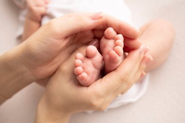 Childrens foot in the hands of mother, father, parents. Feet of a tiny newborn close up. Little baby legs. Mom and her child. Happy family concept. Beautiful concept image of motherhood stock photo.