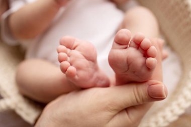 Childrens foot in the hands of mother, father, parents. Feet of a tiny newborn close up. Little baby legs. Mom and her child. Happy family concept. Beautiful concept image of motherhood stock photo.