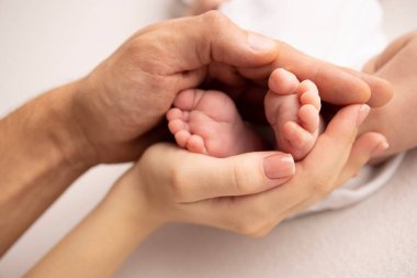 Childrens foot in the hands of mother, father, parents. Feet of a tiny newborn close up. Little baby legs. Mom and her child. Happy family concept. Beautiful concept image of motherhood stock photo.