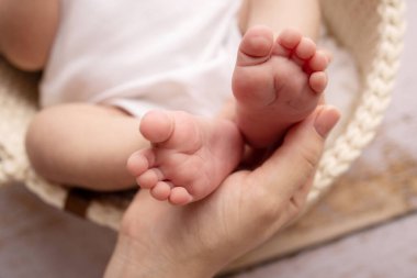 Childrens foot in the hands of mother, father, parents. Feet of a tiny newborn close up. Little baby legs. Mom and her child. Happy family concept. Beautiful concept image of motherhood stock photo.