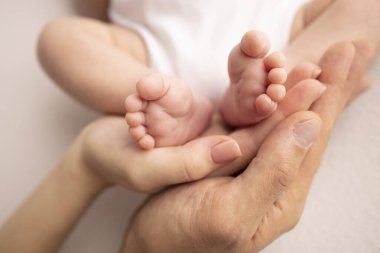 Childrens foot in the hands of mother, father, parents. Feet of a tiny newborn close up. Little baby legs. Mom and her child. Happy family concept. Beautiful concept image of motherhood stock photo.