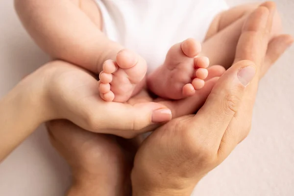 Childrens foot in the hands of mother, father, parents. Feet of a tiny newborn close up. Little baby legs. Mom and her child. Happy family concept. Beautiful concept image of motherhood stock photo.