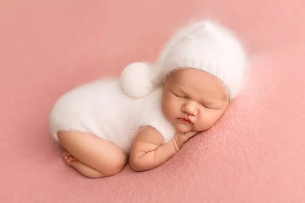 生まれたばかりの赤ん坊の女の子のトップビューは ピンクの背景に 彼女の頭の上に白い帽子で 白い全体に寝ています 小さな新生児の美しい肖像画7日 1週間前 — ストック写真