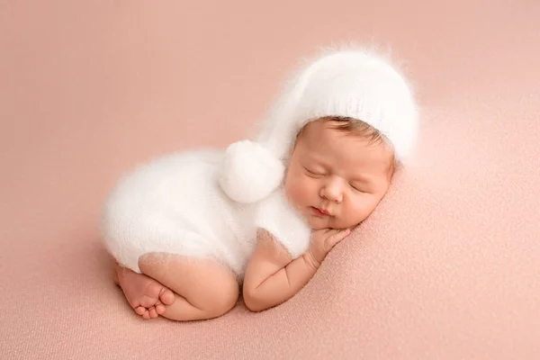 ピンクの背景に白い帽子をかぶった白いジャンプスーツで寝ている新生児の女の子のトップビュー 女の子の美しい肖像画7日 1週間 — ストック写真