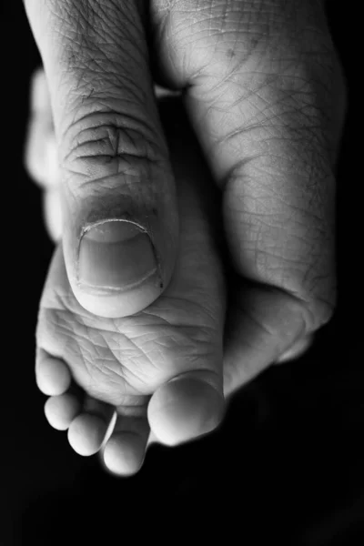 妈妈正在给她的婴儿脚按摩 用黑色的背景把婴儿的脚放在妈妈的手里 预防扁足 肌肉紧张 发育不良 黑白照片 — 图库照片