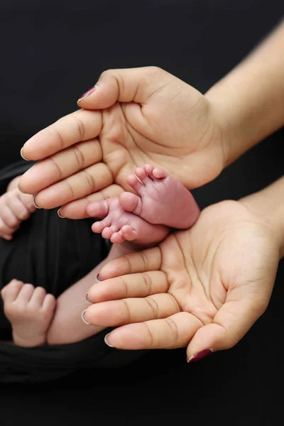 Ладони Родителей Мать Держит Ноги Новорожденного Ребенка Черном Одеяле Черном — стоковое фото