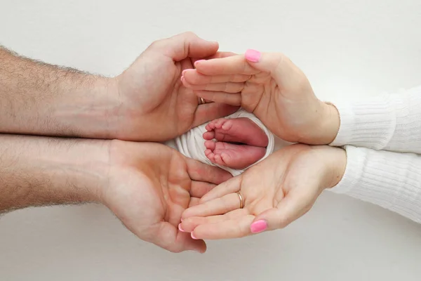 つま先 新生児のかかと 両親の手の中に子供の足 母親と父親の腕の中で赤ん坊の足 ママと子供だ 白地だ マクロ写真 クローズアップ — ストック写真