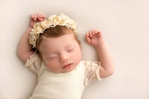 白いスーツを着た可愛い新生児と 頭に花をつけたヘッドバンドが甘い眠りにつく 白い背景にプロのマクロ写真 高品質の写真 — ストック写真