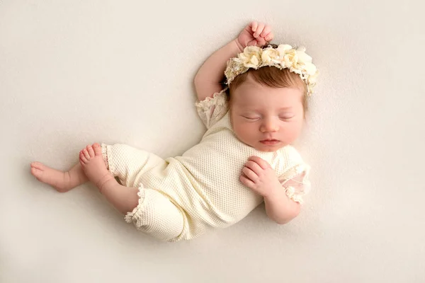白いスーツを着た可愛い新生児と 頭に花をつけたヘッドバンドが甘い眠りにつく 白い背景にプロのマクロ写真 高品質の写真 — ストック写真