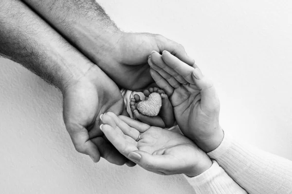 両親の手の中に子供の足 小さな新生児の足を閉じる ニットの心臓を持つ子供の足 母さんの子供だ 幸せな家族の概念 黒と白 母の写真 — ストック写真