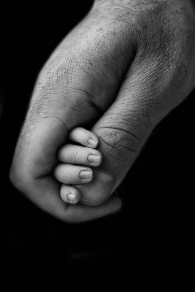 孩子的小手和父母的小手的特写 刚出生的婴儿紧紧抓住父母的大拇指 黑色背景上的黑白摄影 — 图库照片