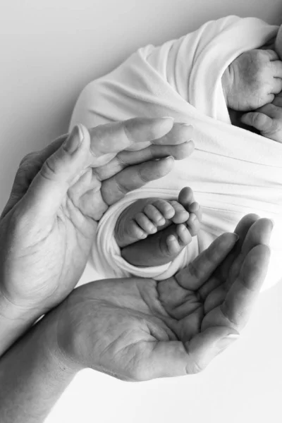 Black and white shade beautiful shape hands of mother, hold tiny newborn baby feet on white background with love, care, family safety and protection, child with premature birth concept or NICU care.