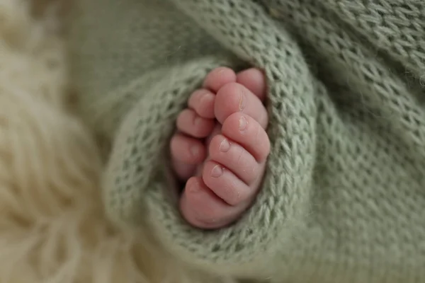 新生儿的小脚 在绿色 开心果 橄榄毛毯的白色花边背景上的新生儿的软脚 新生儿的脚趾 脚跟和脚的宏观照片 — 图库照片
