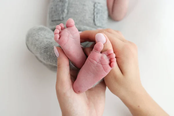 The palms of the father, the mother are holding the foot of the newborn baby on white background. Feet of the newborn on the palms of the parents. Photography of a childs toes, heels and feet