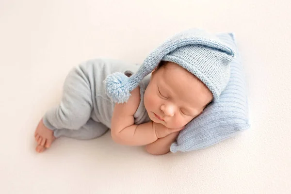 一个可爱的新生男孩在出生的头几天穿着蓝色工作服 背景是白色的面料 蓝色针织帽袋 头顶下的蓝色枕头 高质量的照片 — 图库照片
