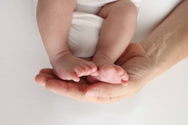 Baba 'nın avuç içi, anne yeni doğan bebeğin ayağını tutuyor. Yeni doğan bebeğin ayakları, ebeveynlerin avuçlarında. Bir çocuğun ayak parmaklarının, topuklarının ve ayaklarının fotoğrafı. Siyah ve beyaz makro. 