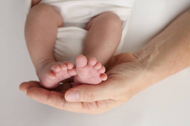 Baba 'nın avuç içi, anne yeni doğan bebeğin ayağını tutuyor. Yeni doğan bebeğin ayakları, ebeveynlerin avuçlarında. Bir çocuğun ayak parmaklarının, topuklarının ve ayaklarının fotoğrafı. Siyah ve beyaz makro. 