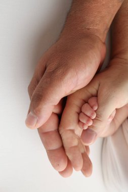 Mutlu bir ailenin üç avuç içi. Minik parmakları olan yeni doğmuş küçük bir el. Ebeveynlerin avuç içi, anne ve baba yeni doğmuş bir bebeğin sapını tutuyor. Stüdyo makro çekimi beyaz arkaplanda. 