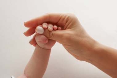 Ebeveynler yeni doğmuş bir bebeğin parmaklarını tutuyor. Bir anne ve babanın eli yeni doğmuş bir bebeğin yumruğunu tutuyor. Aile sağlığı ve sağlık hizmetleri. Beyaz arkaplanda profesyonel fotoğraf. 