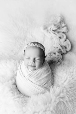 Yaşamın ilk günlerinde beyaz bir koza içinde beyaz bir bandajla uyuyan yeni doğmuş bir kız. Stüdyo makro fotoğraf, yeni doğmuş bir bebeğin portresi. Kadın mutluluğu kavramı. 